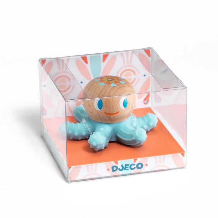The BabySquidi Infant Teether from DJECO, crafted with FSC® Certified Wood for 0+ months, features a smiling wooden octopus with light blue tentacles inside a transparent box adorned with orange and pink patterns. Its octopus shape and floral head design make it both charming and functional.