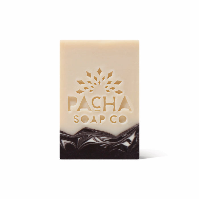 A rectangular, handcrafted Bar Soap by Pacha Soap Co. features a beige top, dark brown marbled bottom, and an embossed sunburst with the brand name. Made with nourishing oils. Presented on a plain white background.