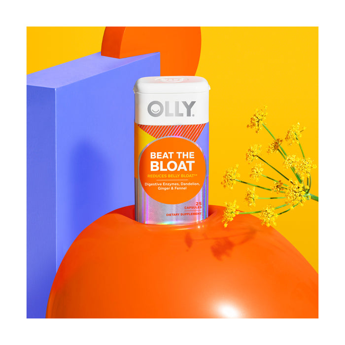 A vibrant display showcases OLLYs Beat the Bloat supplement for digestive health, featuring botanical extracts for bloat relief. The packaging is set on a glossy red surface with a bright yellow and blue geometric background adorned with small yellow flowers.