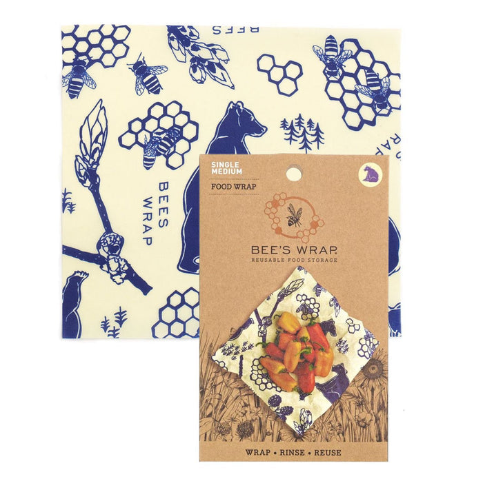 The Single Medium Wrap from Bees Wrap displays blue bee, honeycomb, and bear patterns on a beige background. The eco-friendly package includes a label with a wrapped sandwich and text Bees Wrap, Wrap. Rinse. Reuse, promoting stylish reusable food storage solutions.