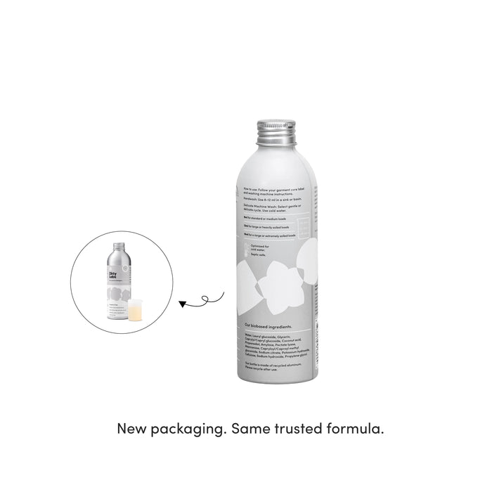 A silver bottle with white graphics, displayed alongside an inset of the same bottle featuring a pump dispenser. Text below reads, New packaging. Same trusted Dirty Labs Bio Laundry Detergent with Phytolase® – Hand Wash & Delicates formula.