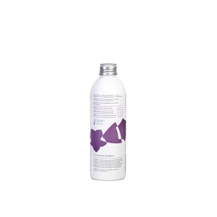 A white bottle with a metallic cap, decorated with abstract purple shapes and minimal text, reflects the clean aesthetic of a premium enzyme laundry detergent. The Dirty Labs Bio Laundry Detergent with Phytolase® – Jasmine, Matcha, Vetiver is photographed against a plain white background.