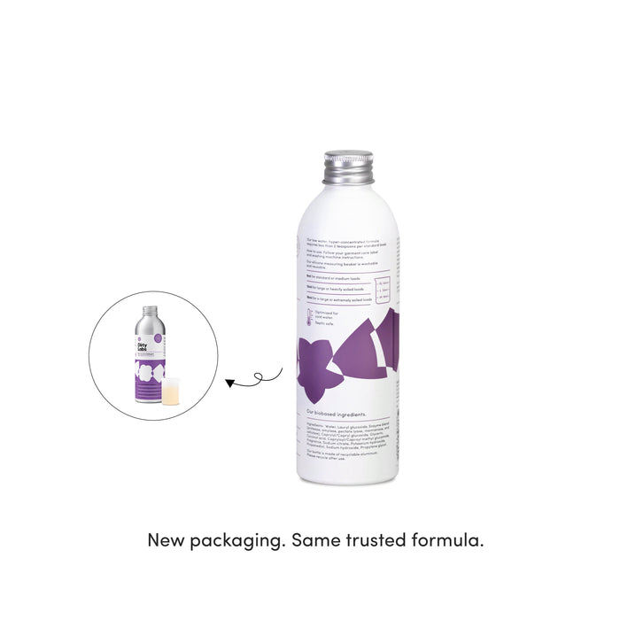 A sleek silver bottle adorned with purple accents represents the new packaging for Dirty Labs Bio Laundry Detergent with Phytolase® – Jasmine, Matcha, Vetiver, displayed beside a small image of the previous packaging. The text below states: New packaging. Same trusted bio laundry detergent formula.
