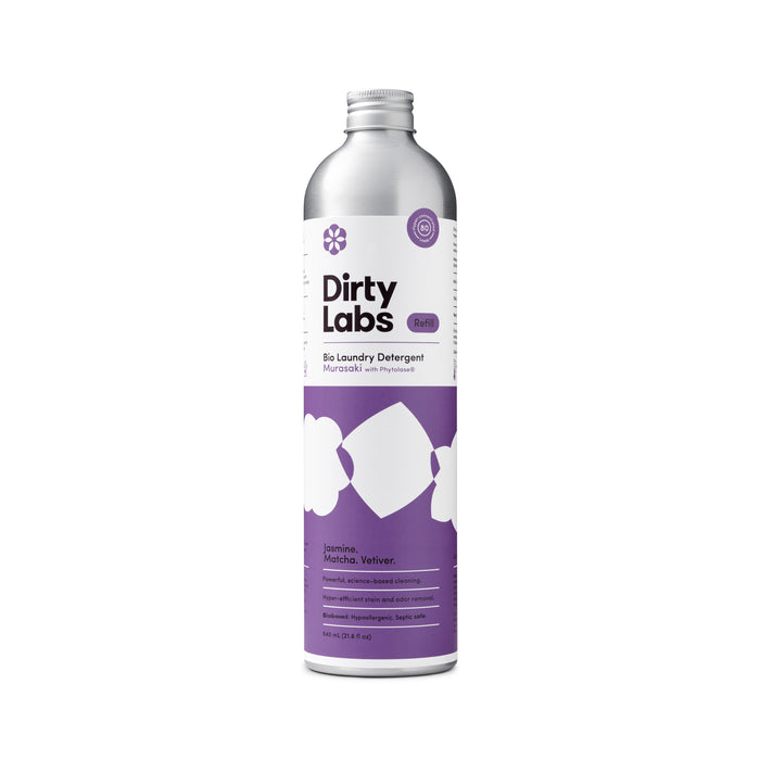 A silver bottle of Dirty Labs Bio Laundry Detergent with Phytolase® in the Jasmine, Matcha, Vetiver scent, featuring a white and purple label adorned with cloud and shirt graphics. The label lists fragrance notes and eco-friendly details, emphasizing this enzyme-based laundry detergent’s gentle yet effective natural cleaning power.