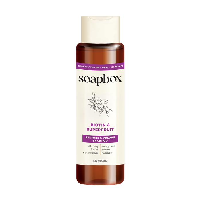 Soapboxs Biotin and Superfruit Restore & Volumize Shampoo offers sulfate-free, color-safe, vegan collagen for extra volume. The brown 16 fl oz (473 mL) bottle has a white label with purple accents and enhances body.