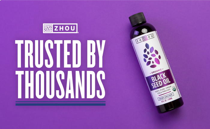 A bottle of Zhou Organic Black Seed Oil is displayed on a purple background. The text reads "Trusted by Thousands" alongside the Zhou logo.