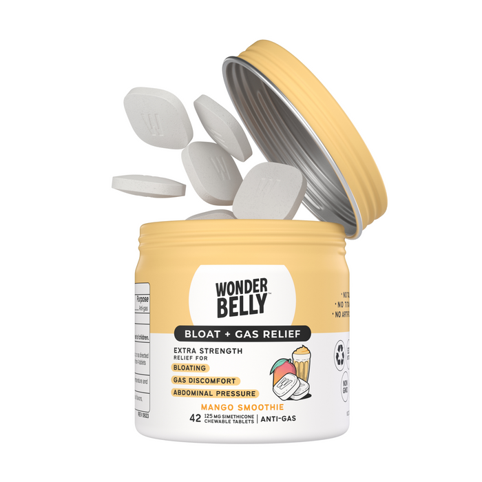A yellow Wonderbelly Bloat + Gas container is open, with tablets pouring out. Designed for Extra Strength Relief, it alleviates bloating, gas, and abdominal pressure using Simethicone tablets. Enjoy 42 chewable delights in Mango Smoothie flavor.