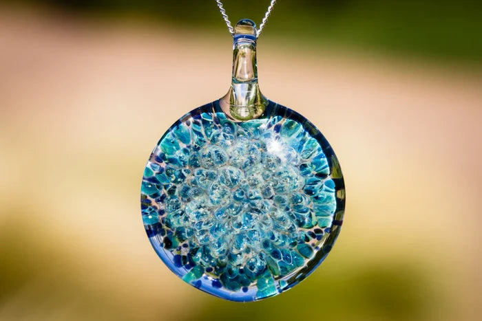 Blue moon pendant infused with cremation ashes featuring a glass disc with blue bubbles on a silver chain