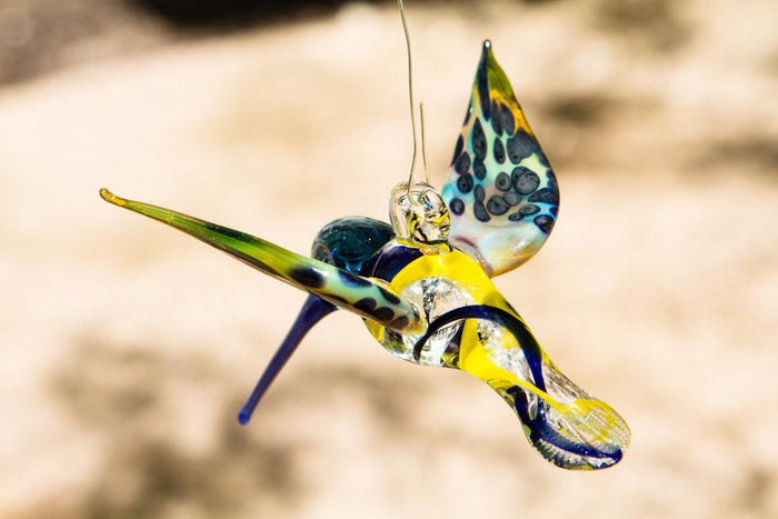 Hanging glass hummingbird ornament with blue and yellow swirls infused with ashes