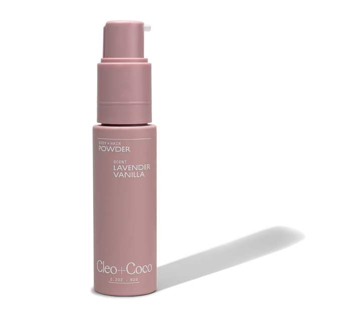 A pink pump bottle of Cleo & Coco Body + Hair Powder in Lavender Vanilla, with white text. Formulated with natural arrowroot powder and an aluminum-free formula for gentle care.