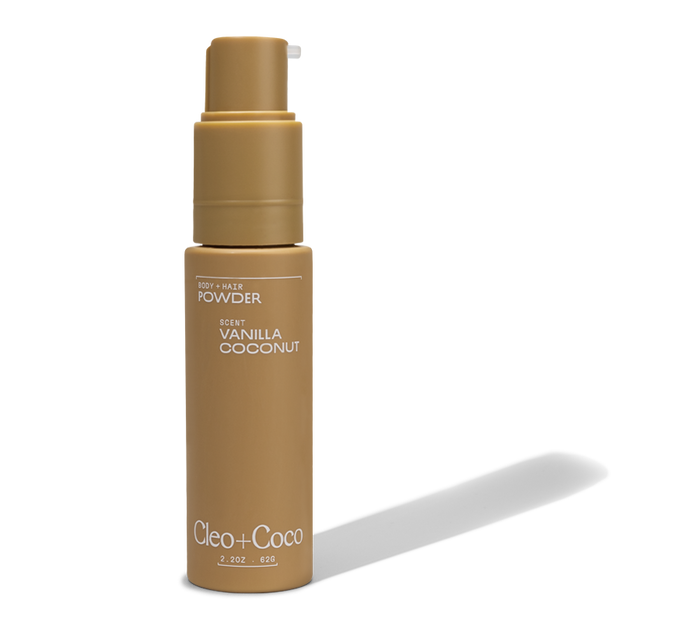 A tan 2 oz bottle of Cleo & Coco Body + Hair Powder in Vanilla Coconut scent, featuring a pump dispenser and made with natural, aluminum-free arrowroot powder.