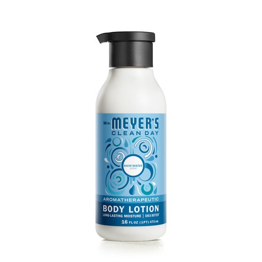 A 16 fl oz white bottle of Mrs. Meyers Body Lotion, Rain Water scent, features a blue label with bubbles and is enriched with shea butter for smooth skin. The garden-inspired fragrance offers long-lasting moisture and is naturally derived.