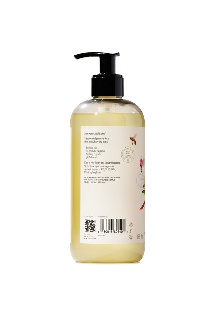A clear plastic pump bottle with a black dispenser, filled with light yellow liquid. The back label shows instructions, ingredients, illustrations, and a QR code—suggesting this is Koala Eco Body Wash.
