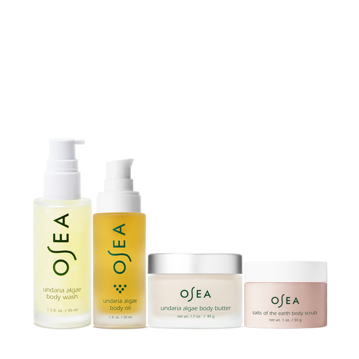 The Bodycare Bestsellers Set by OSEA features Undaria Algae Body Wash, Body Oil, Body Butter, and Salts of the Earth Body Scrub, all elegantly packaged in sleek containers with green and white labeling.