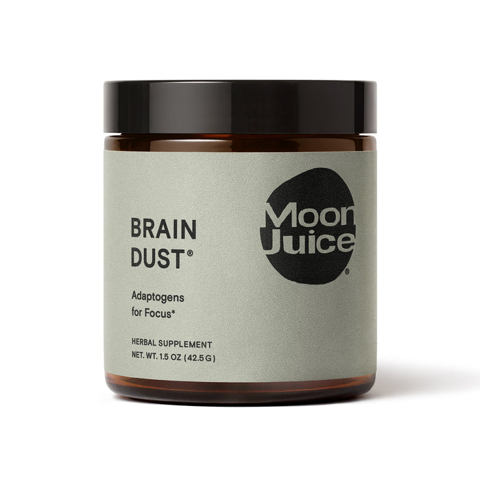 Moon Juice Brain Dust, an adaptogen blend for mental stamina, alertness, and concentration, comes in a jar with a light gray label featuring black text and a round logo. Its labeled as an herbal supplement with a net weight of 1.5 oz (42.5 g).