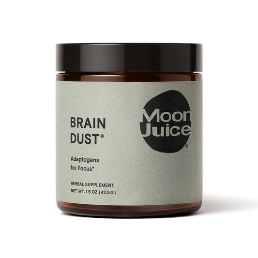 Moon Juice Brain Dust, an adaptogen blend for mental stamina, alertness, and concentration, comes in a jar with a light gray label featuring black text and a round logo. Its labeled as an herbal supplement with a net weight of 1.5 oz (42.5 g).