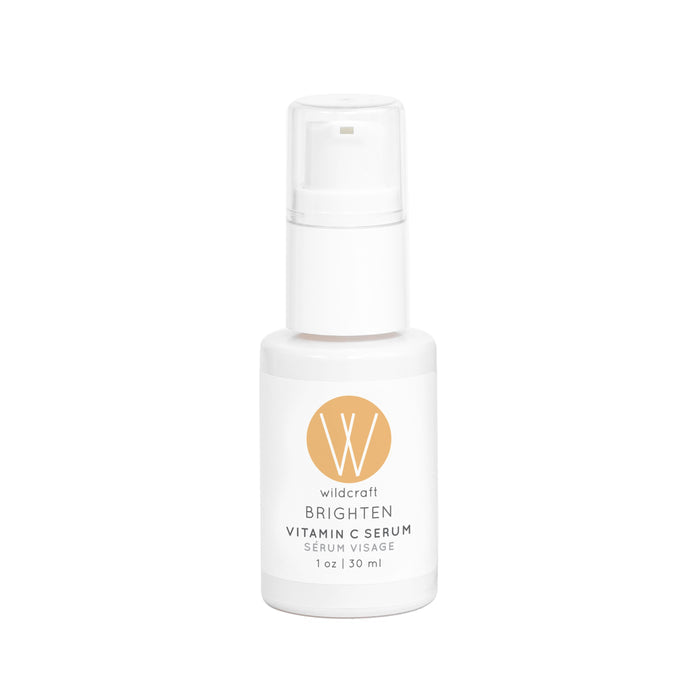 A white bottle of Wildcraft Brighten Vitamin C Face Serum with a pump features an orange circle with a white W logo on the label, and contains 1 oz (30 ml) of skin-brightening serum.