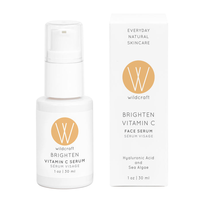 A white bottle of Wildcrafts Brighten Vitamin C Face Serum (1 oz / 30 ml), with a beige label and simple design, enriched with hyaluronic acid and sea algae to brighten skin, sits beside its box.
