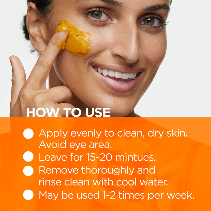 A woman applies an orange facial mask to her cheek while smiling. Text instructions on the image explain how to use the mask: apply to clean skin, avoid eyes, leave for 15-20 minutes, rinse with cool water, and use 1-2 times weekly.