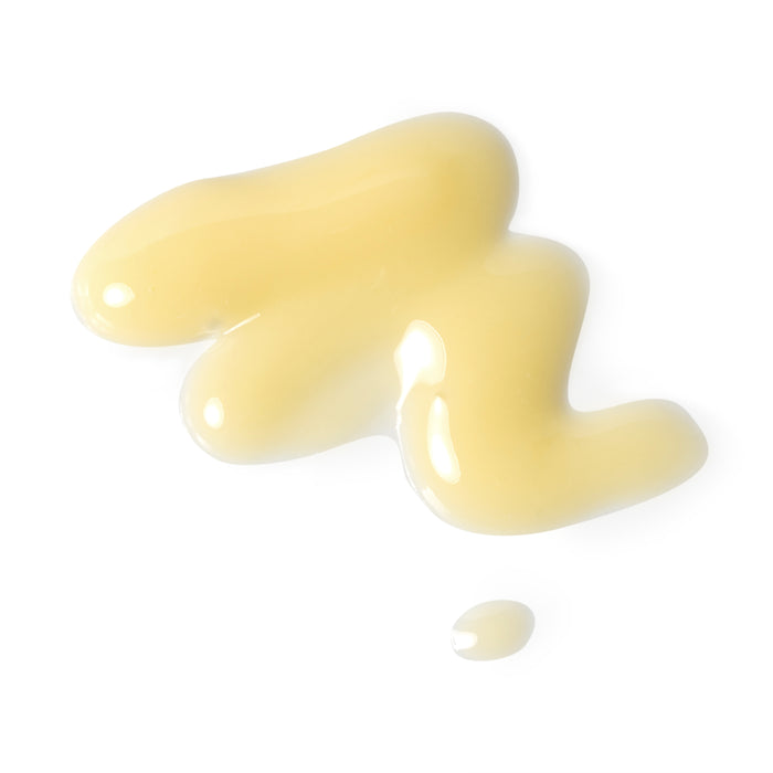 A smooth, glossy blob of Andalou Naturals Brightening Turmeric + C Enlighten Serum in creamy, light yellow spreads on a white background, infused with vitamin C for an illuminating touch.