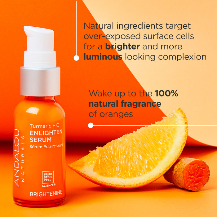 A bright orange bottle of Andalou Naturals Turmeric + C Enlighten Serum is positioned next to a slice of orange and a piece of turmeric. Text highlights natural fragrance of oranges and luminous complexion benefits.