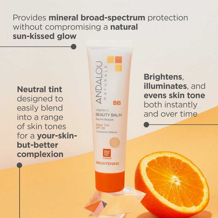 A BB cream tube labeled "ANDALOU Naturals" with brightening Vitamin C and SPF 30. Text highlights its natural glow, neutral tint, and skin benefits. An orange is sliced in half, placed next to the tube on a bright background.