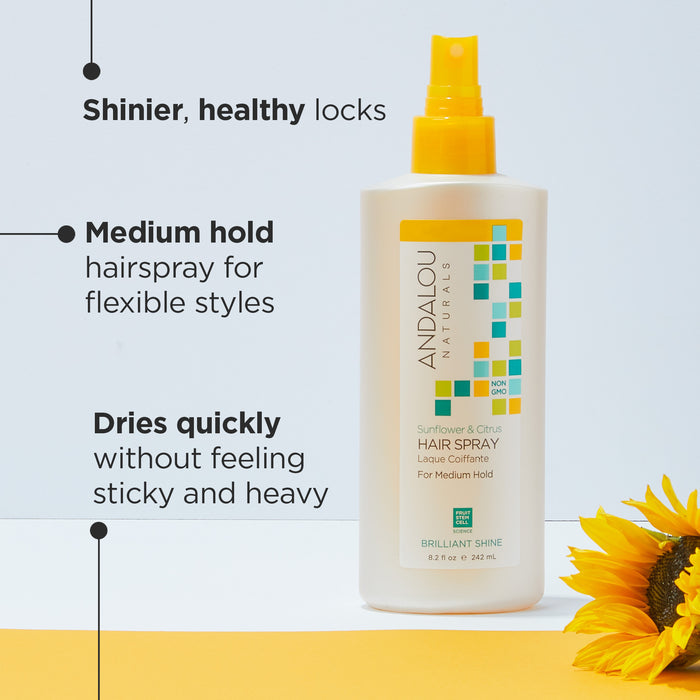 A bottle of Andalou Naturals Sunflower &amp; Citrus Hair Spray is placed against a blue and yellow background. Features listed include shinier, healthy locks, medium hold, and quick drying. A sunflower is partially visible in the bottom right corner.