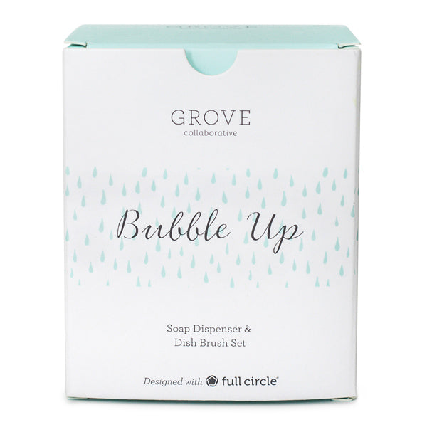 The Grove Co. Bubble Up Dish Soap Dispenser & Brush Set comes in box packaging featuring a minimalist design with a white background, subtle blue raindrop patterns, and elegant text.