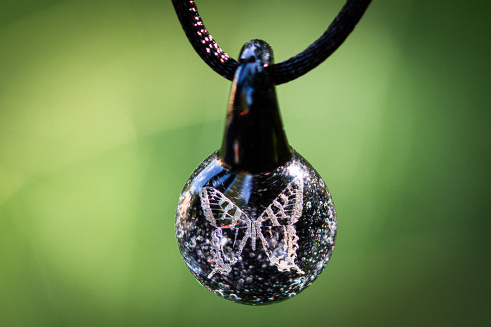 Teardrop glass pendant infused with cremation ash and a holographic butterfly design on a black adjustable cord
