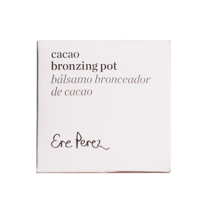 Square packaging of Ere Perezs Cacao Bronzing Pot, a natural bronzing cream, features the text bálsamo bronceador de cacao in English and Spanish. Set against a white background, the black text elegantly highlights this face bronzer.