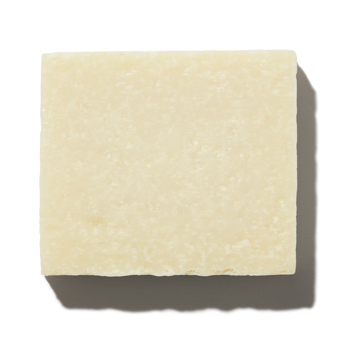 A close-up of the square, cream-colored Calm Body Bar by NOT!CE Hair Co, enriched with sea salt for sensitive skin. Its smooth yet slightly uneven surface casts shadows to the right and bottom against a white background. Ideal for babies and those with sensitive skin.