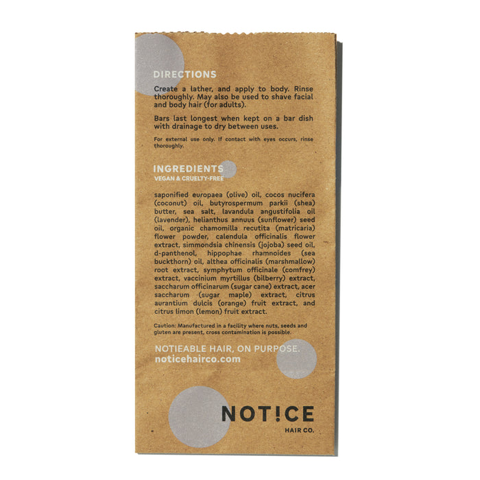 Image of a brown paper featuring directions and ingredients for NOT!CE Hair Cos Calm Body Bar, emphasizing its vegan, cruelty-free formula with sea salt for sensitive skin. The paper also has a circular grey pattern at the top and bottom.
