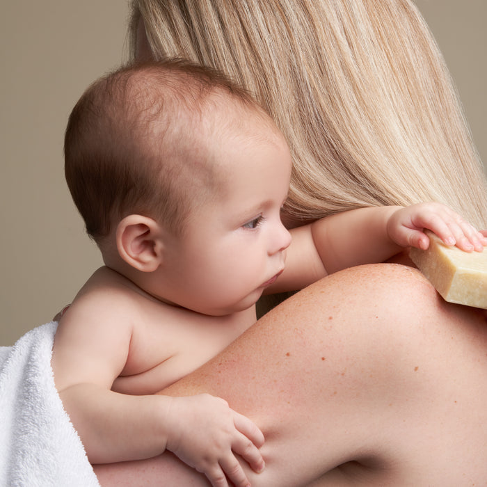 A woman gently cradles her baby, the soothing scent of NOT!CE Hair Cos Calm Body Bar with lavender essential oil lingering in the air, creating a serene atmosphere perfect for delicate moments.