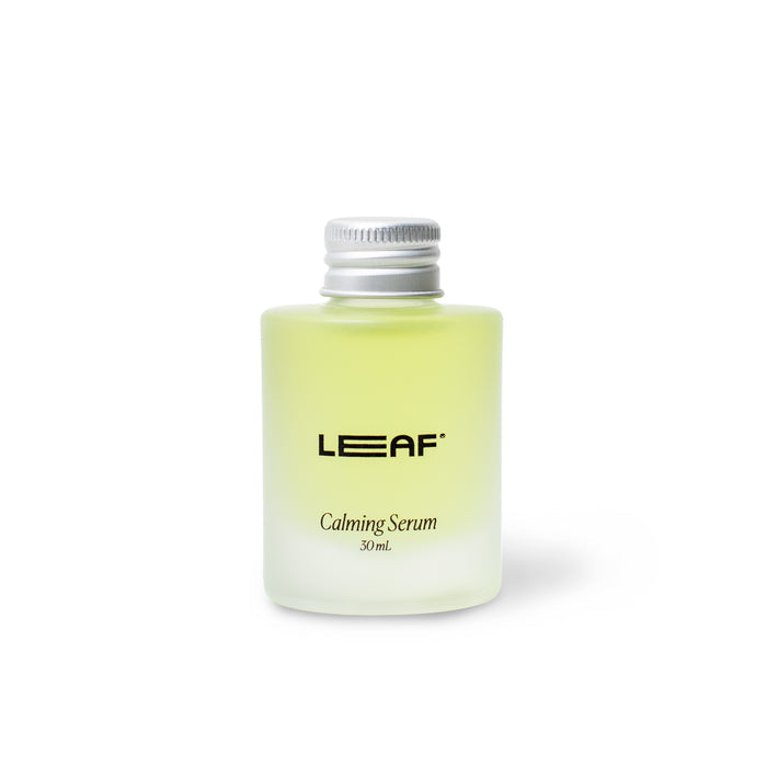 A small, frosted transparent bottle labeled Calming Serum Refill 30 mL, by Leaf Shave, contains a light green liquid enriched with essential oils. Topped with a silver screw cap, it exudes tranquility against a plain white background.