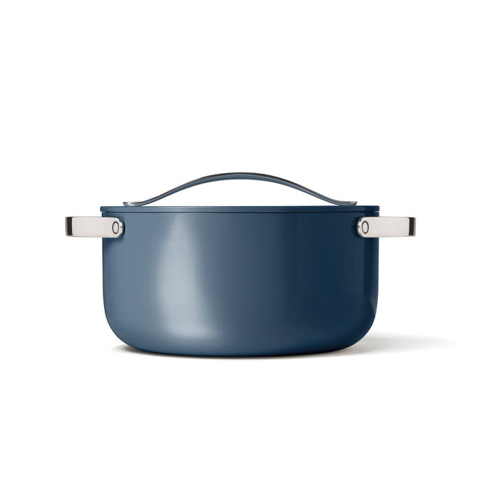Placed against a white background, the Caraway Ceramic Dutch Oven (6.5 qt) showcases its modern design with a curved lid and silver handles. The non-toxic, ceramic-coated pot is blue with a naturally non-stick surface.