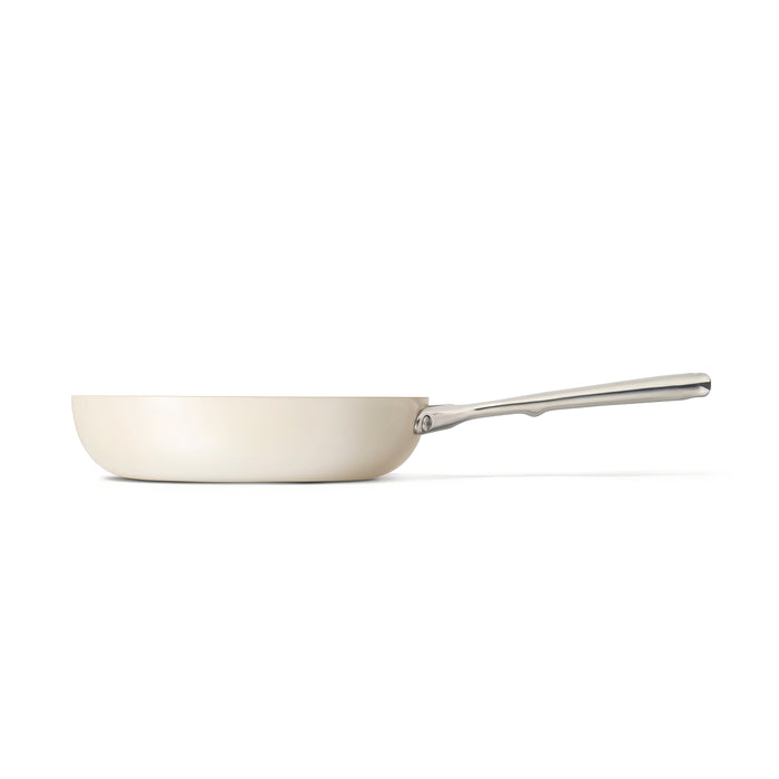 A side view of the Caraway Ceramic Fry Pan, 10.5, displays a cream hue with a silver handle against a white background. Its ceramic-coated interior ensures non-toxic, naturally non-stick cooking in a minimalist, modern design.