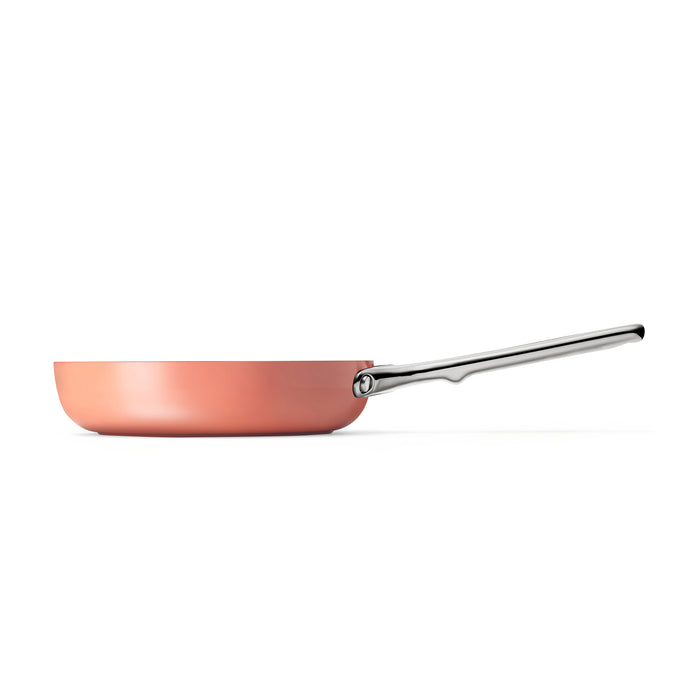 A side view of the Caraway 8 Ceramic Fry Pan features a copper hue with a long silver handle, set against a white background.