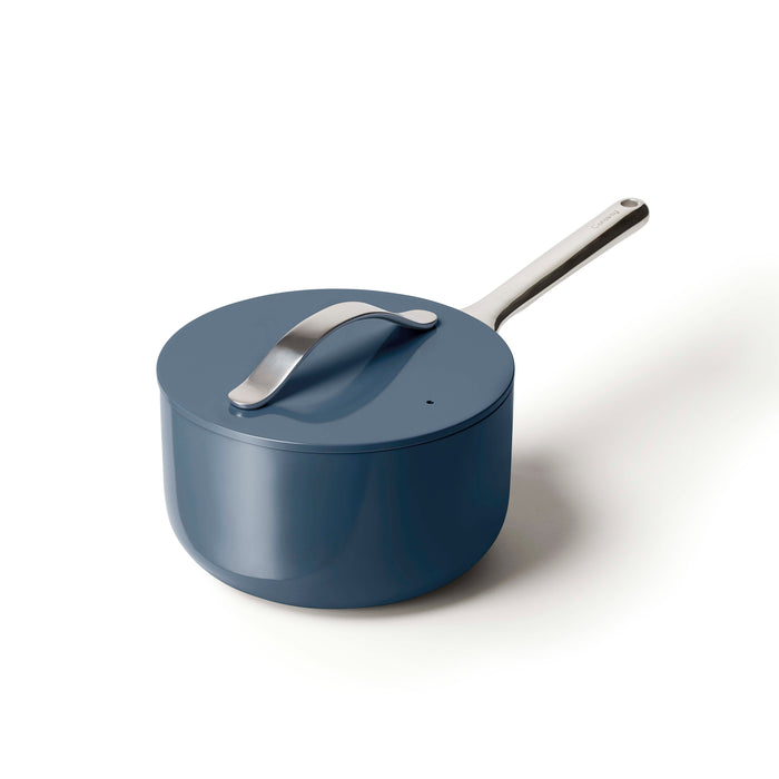 The Caraway Ceramic Sauce Pan, 3 qt, in blue, features a non-toxic ceramic-coated interior and non-stick pot. Its matte finish contrasts with the sleek silver handle. A matching lid includes a curved handle for easy lifting.