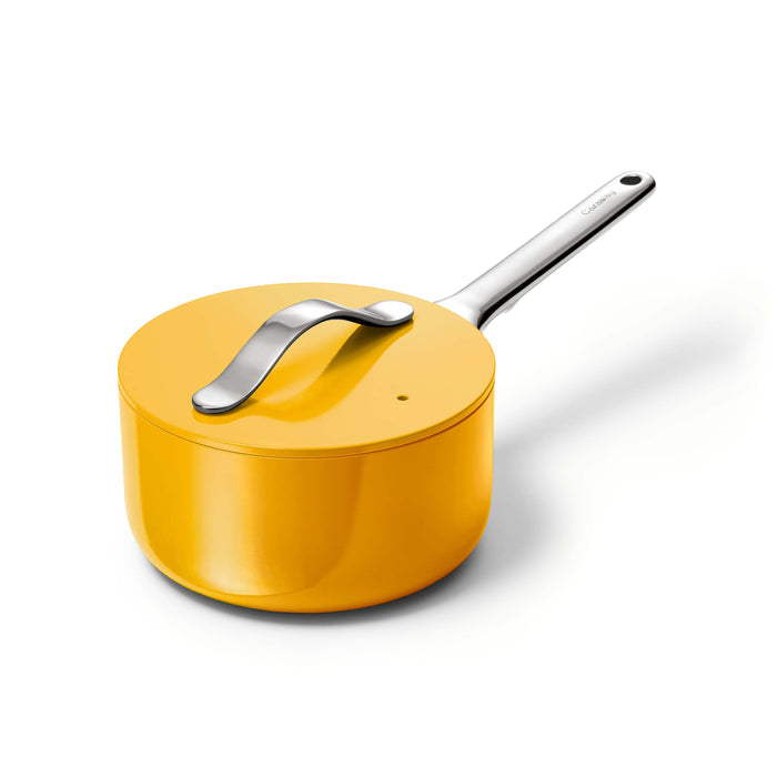 The Caraway Ceramic Sauce Pan, 1.75 qt, features a yellow finish with a sleek metal handle and matching lid on a white background. The shiny straight pot handle and the curved lid handle complement its non-stick, non-toxic coating for healthy cooking every time.