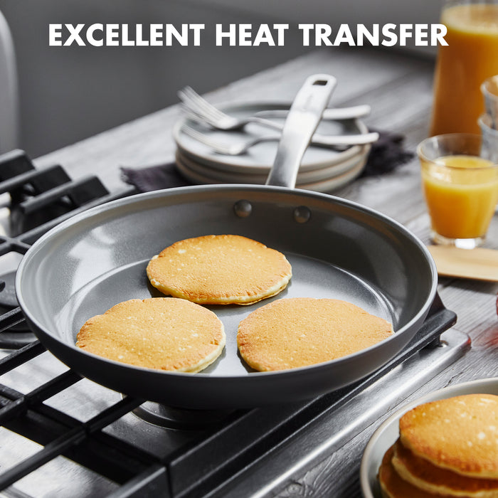 The GreenPan Chatham 12" Open Frypan evenly cooks pancakes on the stovetop, with plates, a glass of orange juice, and more pancakes in the background. "EXCELLENT HEAT TRANSFER" appears at the top.