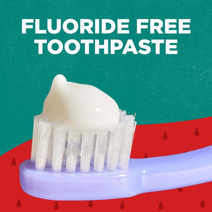 A toothbrush with white toothpaste is shown against a green and red background with water droplets. The text above reads "Fluoride Free Toothpaste.