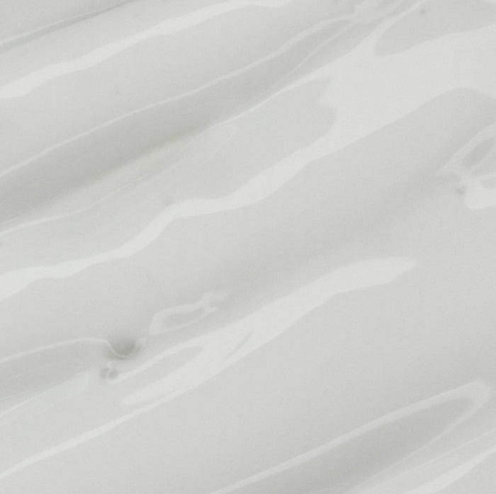 Close-up of a glossy white surface with gentle wavy textures, resembling a liquid blend of hydrating coconut oil, reflecting aloe veras soothing essence and the subtle tone variations of Weledas Citrus Refreshing Body Lotion.
