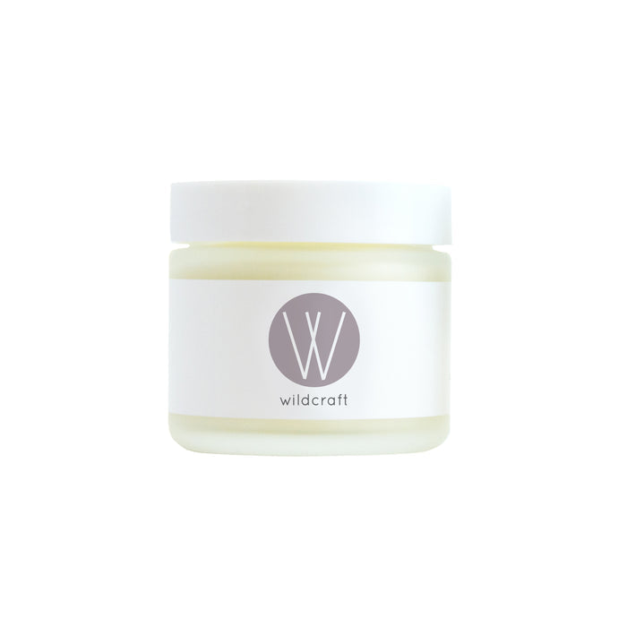 A small jar of Wildcrafts Clarify Face Cream, featuring a white label and gray logo, rests elegantly. The jar has a white cap containing a light yellow cream ideal for sensitive skin, all set against a plain white background that emphasizes the products simplicity and purity.
