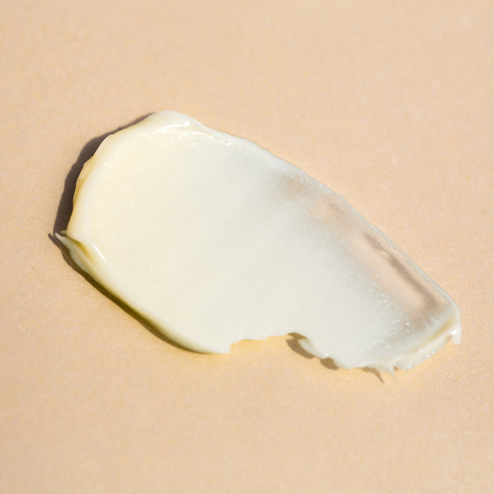 A smooth, creamy white substance spread over a light beige surface, with a thick and slightly glossy texture. This suggests it could be Clarify Face Cream by Wildcraft, ideal for sensitive skin.