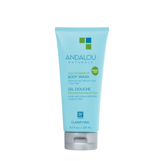 The blue 8.5 fl oz (251 ml) tube of Andalou Naturals Clarifying Yuzu Grapefruit Body Wash contains detoxifying salicylic acid and tea tree, with a bilingual English-French label highlighting its commitment to clean skincare.
