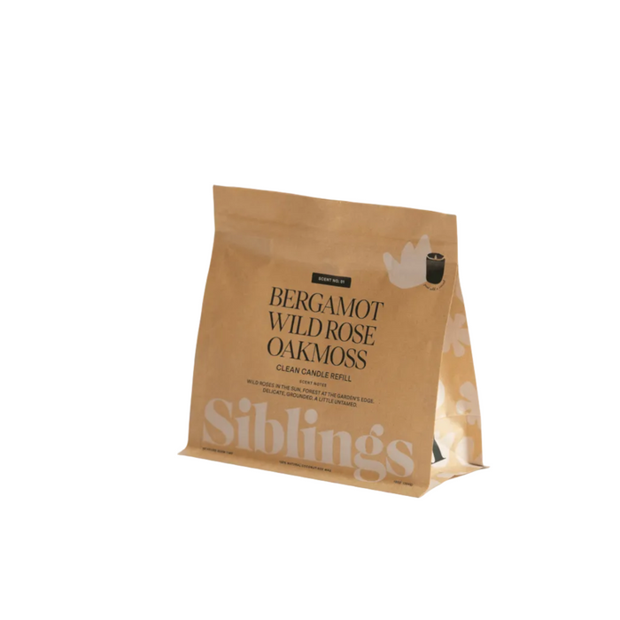 A tan pouch labeled Siblings DIY Candle Kit with text Bergamot Wild Rose Oakmoss Clean Candle Refill, in compostable packaging. The pouch stands upright against a white background.