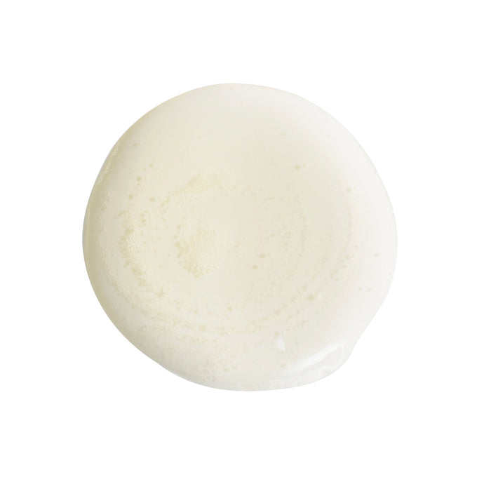 A circular splash of white liquid on a plain background, reminiscent of Mad Hippies Cleansing Oil, has smooth edges and a creamy, glossy texture, symbolizing the essence of organic skincare craftsmanship.
