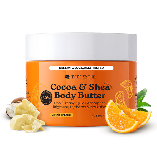 A jar of Tree To Tub Moisturizing Coconut, Cocoa & Shea Butter Body Butter with a white lid is surrounded by cocoa beans, shea butter pieces, aloe vera, and orange slices. The label highlights hydration for dry skin.
