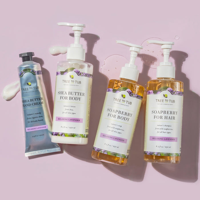 Four Tree To Tub products are showcased against a light background: the Cocoa & Shea Butter Anti-Aging Hand Cream for Dry Hands, two shea butter body lotions, and two soapberry shampoos, all with a relaxing lavender scent.