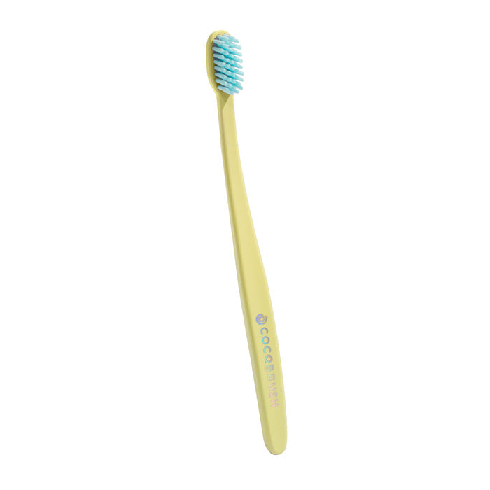 A Cocobrush Toothbrush by Cocofloss, featuring a straight yellow handle with COCO branding in light blue, is designed for children. It has soft blue multi-density bristles and is shown angled against a white background.